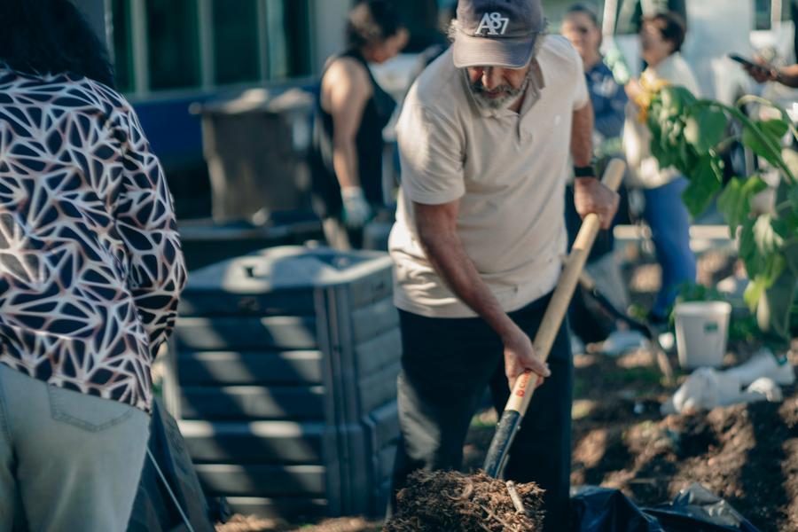 Three participants examine a bowl of finished compost up close.